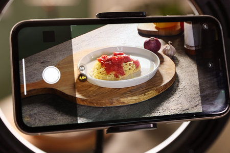 Shooting tasty pasta and ingredients with smartphone in studio, selective focus. Professional food...
