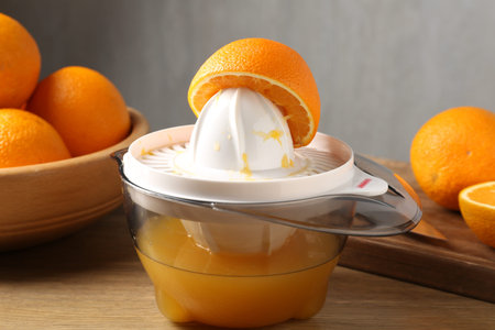 Making juice. Juicer and fresh oranges on wooden table, closeup