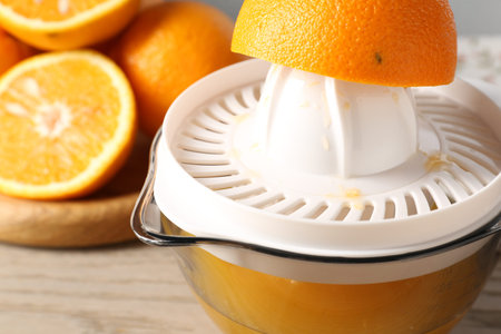 Making juice. Juicer and fresh oranges on wooden table, closeup