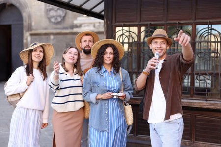 Guide with microphone and group of tourists on city street during excursion