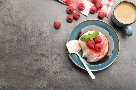 Delicious panna cotta with berries, sauce and mint on gray textured table, flat lay. Space for text