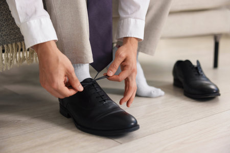 Getting ready. Young man putting on stylish shoes at home, closeupの写真素材