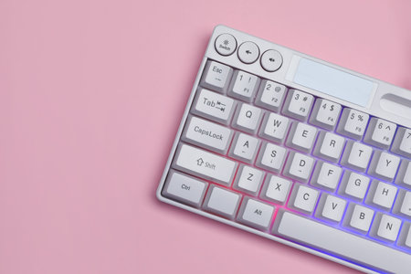 White keyboard with RGB lighting on pink background, top view. Space for text