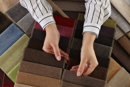 Woman choosing fabric among different samples indoors, top view