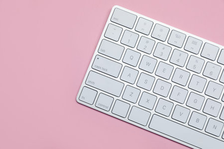 Modern white wireless keyboard on pink background, top view. Space for text