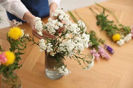 Florist making bouquet of flowers at wooden table, above viewの写真素材