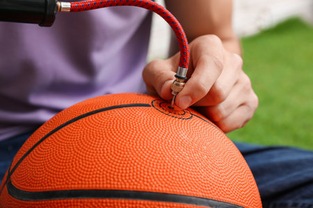 Man inflating basketball ball with manual air pump indoors, closeupの写真素材