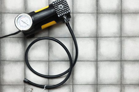 One tire inflation gun with gauge on light tiled background, top view. Space for textの写真素材