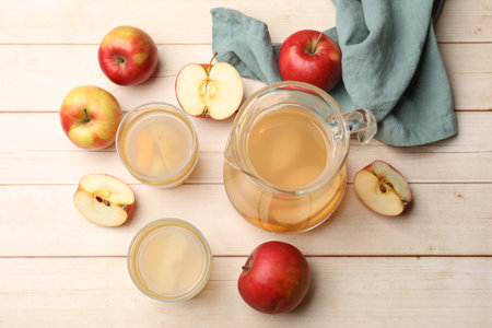 Tasty compot in glasses, jug and fresh apples on wooden table, flat lay