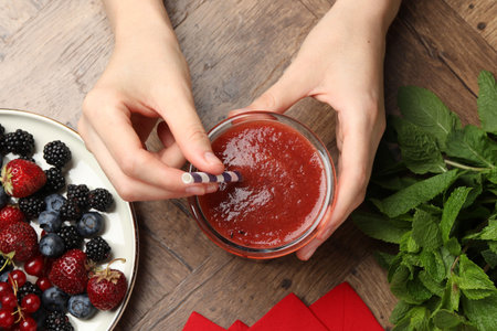 Superfood. Woman with tasty smoothie and ingredients at wooden table, top view