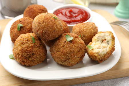 Delicious fried croquette balls with parsley and ketchup on gray textured table, closeup