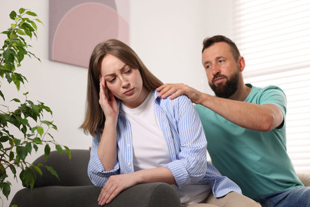 Betrayal. Husband apologizing to his offended wife on sofa at homeの写真素材