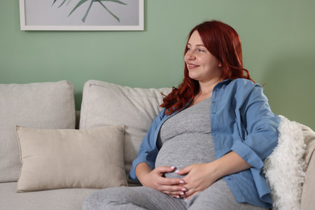 Beautiful pregnant woman on sofa at homeの写真素材