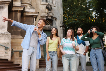 Guide with microphone and group of tourists on city street during excursion