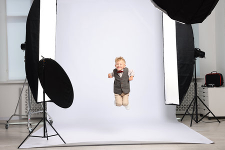 Little boy on white background in photo studio with professional equipmentの写真素材