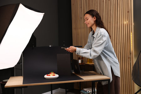 Woman taking picture of tasty pasta with smartphone in studio. Professional food photographyの写真素材