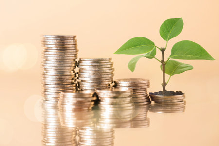 Savings concept. Stacked coins and green sprout on beige background