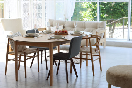 Beautiful table setting, chairs and decor in dining room. Interior design