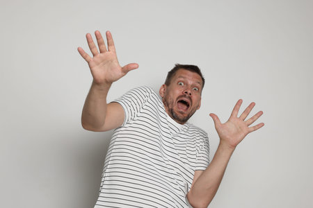 Man suffering from panic attack on light grey background