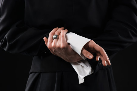 Young man wearing stylish suit and ring on black background, closeup