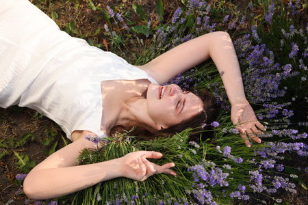 Beautiful young woman lying among lavender flowers outdoors, above viewの写真素材