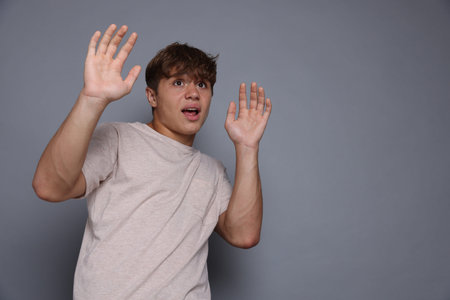 Teenage boy suffering from panic attack on grey background. Space for textの写真素材