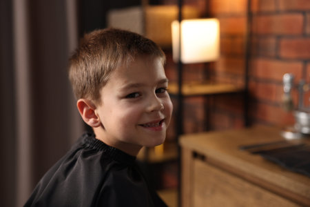 Portrait of cute little boy in barbershop, space for textの写真素材