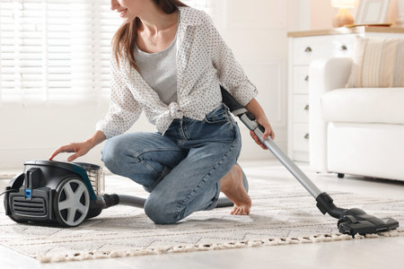 Woman cleaning carpet with vacuum cleaner at home, closeupの写真素材