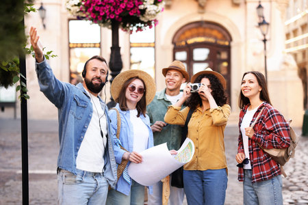 Guide with headset and group of tourists on city street during excursionの写真素材