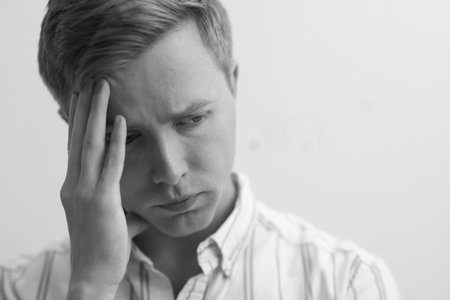 Sad tired man on grey background. Black and white effect
