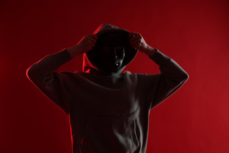 Anonymity. Woman wearing mask on red backgroundの写真素材