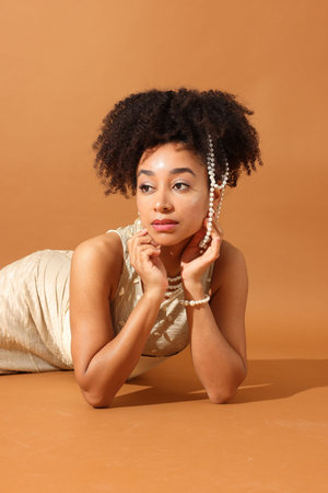 Fashionable portrait of beautiful Brazilian woman in stylish outfit on light brown backgroundの写真素材