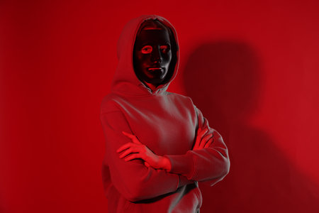 Anonymity. Woman wearing mask on red backgroundの写真素材