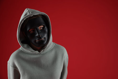 Anonymity. Woman wearing mask on red background, space for textの写真素材