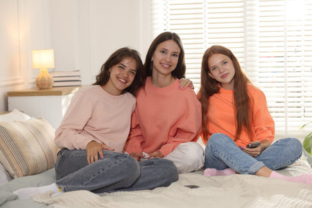 Portrait of happy friends on bed at homeの写真素材