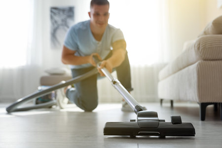 Man cleaning floor with vacuum cleaner at home, selective focusの写真素材
