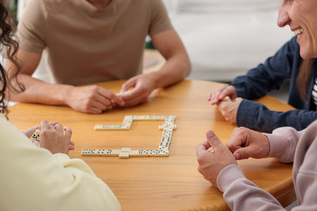 Friends playing dominoes at wooden table indoors, closeupの写真素材