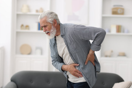 Senior man suffering from back pain at homeの写真素材