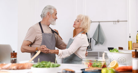 Elderly couple dancing after cooking together in kitchenの写真素材
