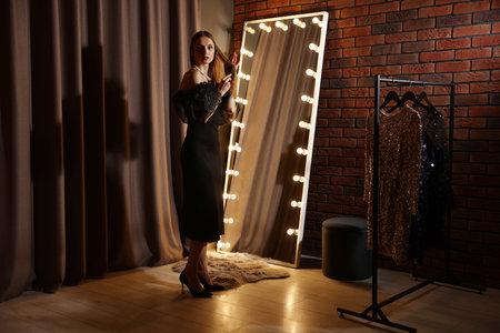 Beautiful woman brushing her hair while getting ready near mirror indoorsの写真素材