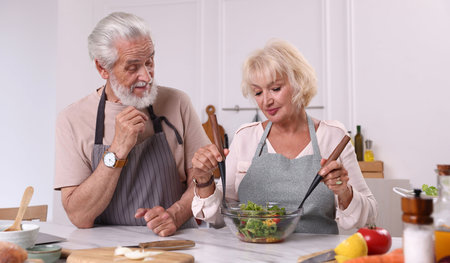 Elderly couple cooking together at marble table in kitchenの写真素材