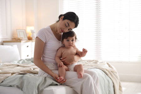Mother with her cute little baby on bed indoorsの写真素材