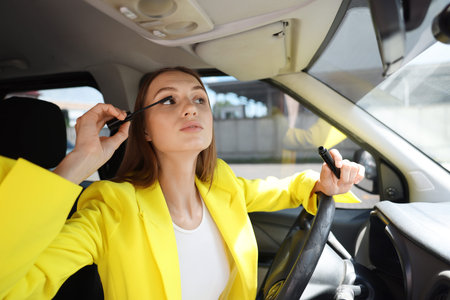 Getting ready. Young woman applying mascara in car
