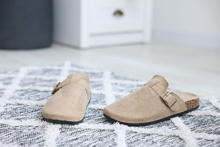 Stylish beige slippers on floor indoors, closeup