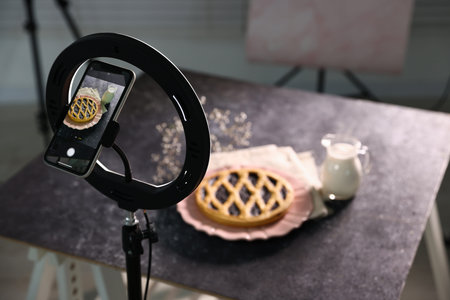 Shooting tasty pie and milk with smartphone in studio, selective focus. Professional food...