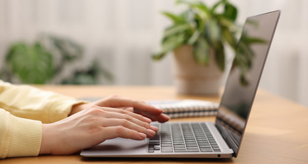 Copywriter using laptop at wooden table indoors, closeupの写真素材