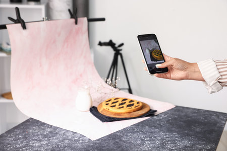 Woman taking picture of tasty pie and milk in studio, selective focus. Professional food photographyの写真素材