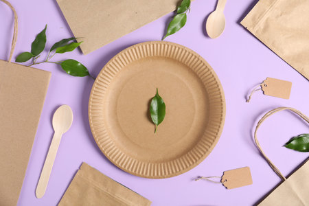 Different eco friendly packaging and leaves on violet background, flat lay