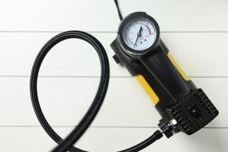 One modern tire inflator on white wooden background, top view