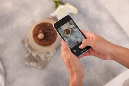 Man taking picture of chocolate cake in studio, top view. Professional food photography